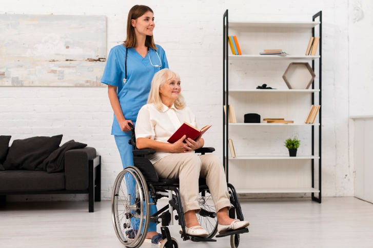 Healthcare worker assisting a patient in a wheelchair down a hallway