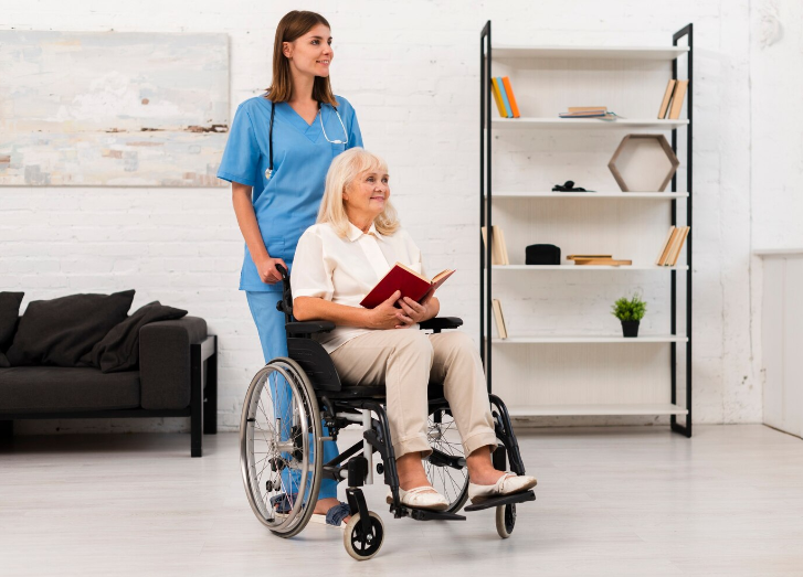Healthcare worker assisting a patient in a wheelchair down a hallway